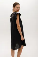 Vestido corto celeste de lino, corte suelto, con cuello redondo con volados y lazo, mangas cortas con volados.