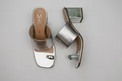 Sandalias negras con taco cuadrado y tira ancha sobre el empeine. Presentan una tira fina que separa el dedo gordo del resto y un aplique metálico plateado.