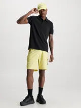 Chomba de algodón piqué negro con cuello de dos botones y insignia de Calvin Klein en la manga.