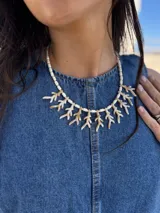Collar corto con cuentas blancas y colgantes de resina color marfil con forma de coral. Se cierra con cadena de acero quirúrgico y ganchito para regular el largo.