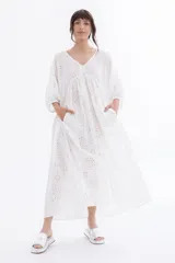 Vestido largo blanco con bordado calado tipo broderie, escote en V y mangas largas abullonadas.