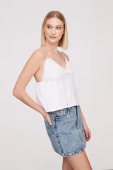 Musculosa blanca de breteles finos con detalles de encaje en el escote y bordado calado en el cuerpo.