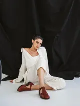Sandalia roja de cuero vacuno con diseño de tiras entrecruzadas y hebilla lateral. Tiene suela de cuero artesanal y taco bajo.