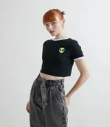 Remera corta negra de algodón con cuello redondo y mangas cortas con ribete blanco. Estampa frontal de la cara de ET.