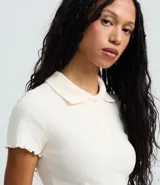 Blusa femenina de algodón certificado, color azul, con cuello polo, cierre de botones y mangas cortas con acabado ondulado.