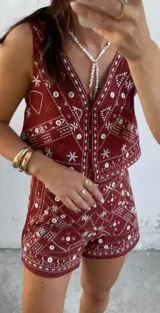 Conjunto de chaleco y short color ladrillo con bordados blancos de motivos geométricos y florales.