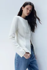 Saco blanco de punto bouclé con cuello redondo, botones forrados hasta la cintura y corte acampanado en la parte inferior.