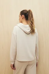 Canguro marrón con capucha, corte amplio y detalle de recorte frontal.