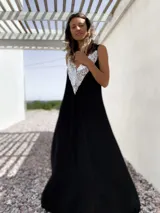 Vestido largo negro con escote en V y breteles finos. Presenta un aplique triangular de lentejuelas plateadas en la parte superior.