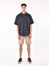 Camisa de manga corta color negro, con cuello camisero y un bolsillo de parche en el pecho izquierdo. Presenta un corte holgado (oversize).