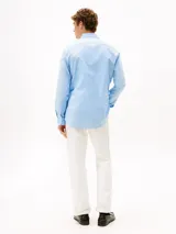 Camisa celeste de algodón Oxford con corte regular y mangas largas. Tiene cuello abotonado, cierre con botones y logo de Tommy Hilfiger bordado en el pecho.