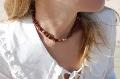 Collar corto ajustable con cuentas irregulares de jaspe rojo y un espaciador cilíndrico de bronce.