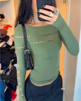 Remera negra de mangas largas con escote asimétrico y aberturas circulares.