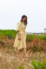 Vestido túnica a rayas verticales color mostaza y blanco, con cuello redondo, mangas cortas abullonadas y lazo para atar en la cintura.