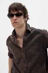 Camisa de jean marrón con lavado gastado, corte oversized, mangas largas y bordado verde con la palabra "PASTICHE" en el pecho.