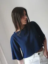 Top color beige de tejido de punto, con mangas cortas y cuello redondo. Presenta un bordado del escudo en la parte delantera.