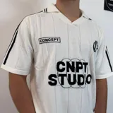 Chomba negra tejida con cuello tipo polo, mangas cortas con rayas blancas y logo estampado en el pecho.