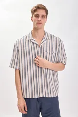 Camisa casual de manga corta con cuello solapa y cierre abotonado. Diseño a rayas verticales en tonos crudo y azul.