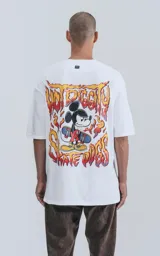 Remera blanca de algodón con cuello redondo y calce oversize. Estampado en la espalda de Mickey Mouse andando en skate con llamas y texto "Hot Diggity Skate Dogs".