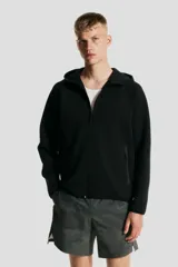 Campera deportiva negra con capucha, cierre frontal, bolsillos con cierre y mangas raglán. Confeccionada en tejido funcional efecto neopreno DryMove™ que ayuda a absorber el sudor.