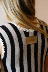 Vestido corto de algodón tejido en punto jersey con diseño de rayas verticales rojas y blancas. Terminaciones en crochet hechas a mano con detalle de lurex. Cuello redondo, sin mangas y silueta trapecio.