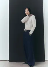 Sweater color crema de punto trenzado con cuello Perkins y mangas largas con puños elásticos.