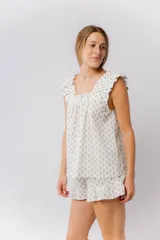 Pijama de algodón estampado con pequeñas flores en tonos pastel. Incluye una musculosa con escote recto, frunces y breteles, y un short con elástico en la cintura y terminación con volado.