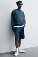 Bermuda azul petróleo de corte relaxed fit, confeccionada en algodón. Tiene cintura elástica ajustable con cordón, bolsillos laterales y un bolsillo trasero.