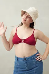 Top de bikini negro con textura, breteles finos y aro metálico en el centro del busto.