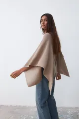 Poncho de tejido de punto color beige con hilo lurex plateado, de corte asimétrico y mangas amplias.