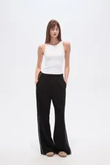Pantalón deportivo negro de corte ancho y tiro alto, con cintura elástica y cordón ajustable. Presenta una raya blanca vertical a cada lado.