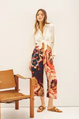 Pantalón capri con estampado floral en tonos naranja, rojo, azul y marrón. Tiene corte regular, bolsillos laterales y elástico en la parte trasera de la cintura.