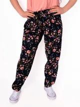 Pantalón babucha negro con estampado floral en tonos rosa, celeste y verde. Tiene cintura elastizada y corte holgado.