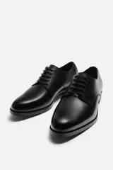 Zapato de vestir marrón tipo derby, con parte superior lisa, horma en punta y suela con ligero tacón.