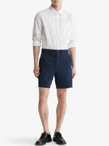 Short de vestir azul marino, de corte recto, con bolsillos laterales y traseros. Se ajusta a la cintura con cinturón de cuero marrón.
