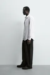 Camisa blanca de manga larga, corte slim fit, con cuello italiano y cierre frontal de botonadura.