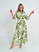 Vestido largo camisero con estampado floral en tonos rosados y blancos, con cuello camisero, manga 3/4 y falda escalonada. Incluye cinturón fino de soga.