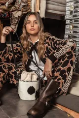 Cartera tipo canasta color terracota con textura símil piel de cocodrilo, con forro de tela blanca ajustable con cordón. Tiene correa larga de cuero marrón con hebilla dorada.