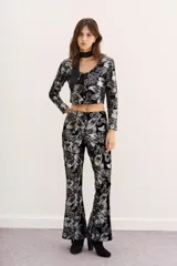 Pantalón de terciopelo negro con estampado floral plateado, corte acampanado y tiro alto.