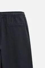 Pantalón largo verde oscuro de algodón con textura, corte recto y cintura elástica ajustable con cordón.