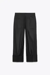 Pantalón color beige de corte ancho, con tiro medio, trabillas en la cintura y raya planchada.