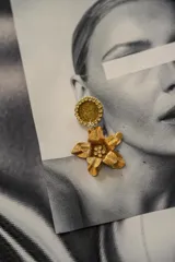 Pendientes con diseño de flor dorada y detalle de brillantes en la parte superior.