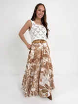 Falda larga de algodón con estampado floral en tonos marrón y blanco. Tiene elástico en la cintura y viene con un cinto de rafia elastizado desmontable.