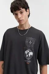 Remera negra de manga corta con corte oversize y estampado gráfico blanco en el frente que incluye un mapa del mundo y figuras geométricas.