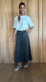 Pollera larga de denim color gris oscuro, con corte acampanado y paneles verticales.