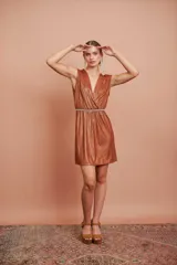 Vestido corto color cobre con escote en V, sin mangas y cinturón fino con strass.