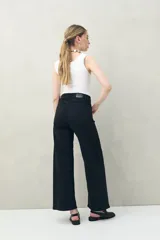 Pantalón de jean azul oscuro, de corte ancho y tiro alto, con bolsillos delanteros cuadrados y amplios.