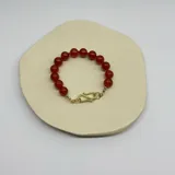 Pulsera elástica con cuentas redondas de ágata roja y cierre de acero hipoalergénico con baño de oro.