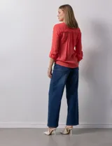 Blusa blanca de gasa marca Zac & Rachel, con cuello a la base, escote en V, abertura central con botones, bolsillo aplicado en el pecho y mangas largas regulables con presilla y botón. Tiene terminación opcional de nudo en el ruedo.