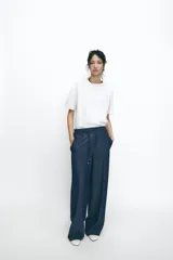 Pantalón de tiro alto azul denim, con cintura elástica ajustable con cordón, bolsillos laterales y traseros, y pernera ancha.